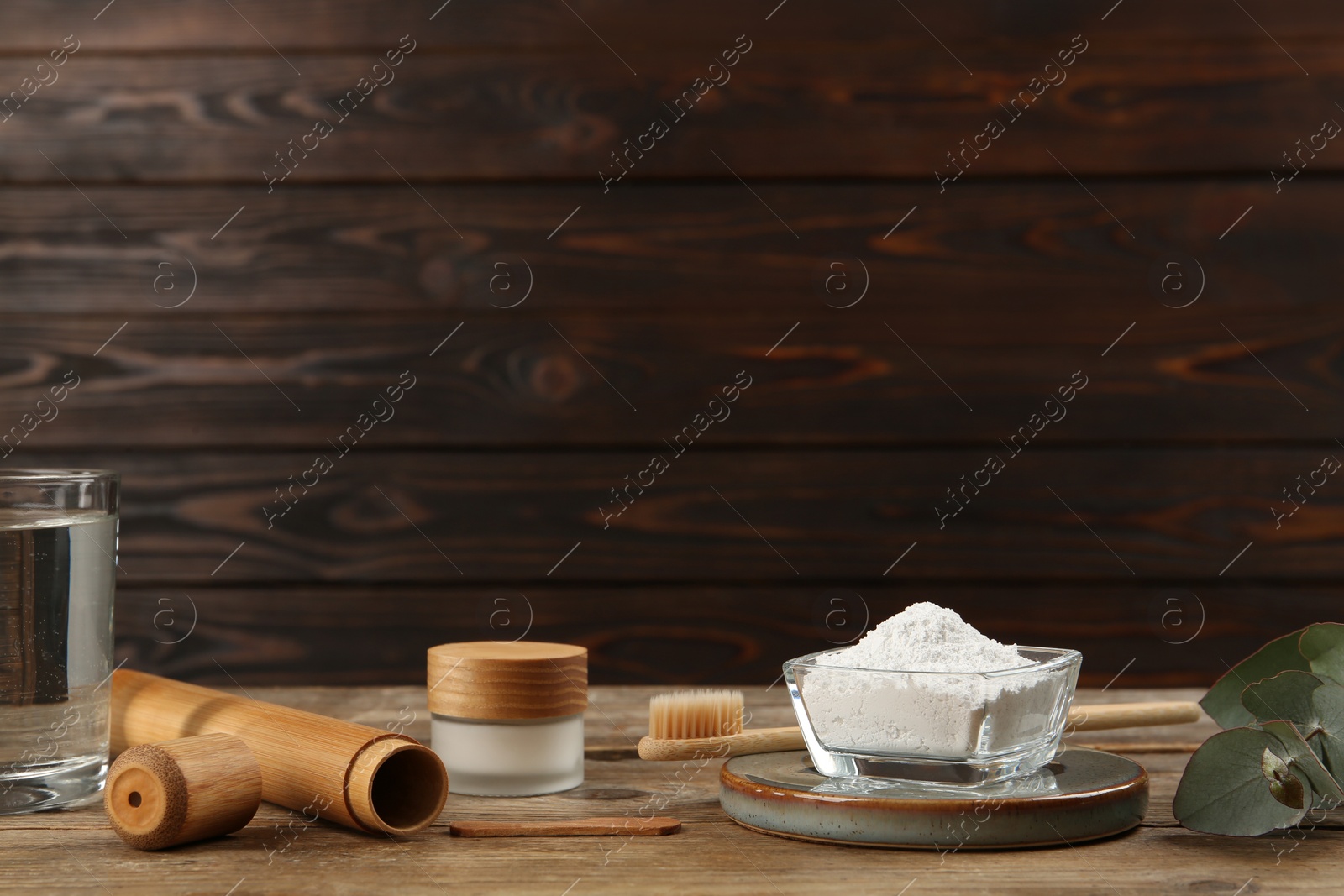 Photo of Composition with tooth powder and eucalyptus on wooden table, space for text