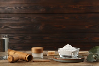 Composition with tooth powder and eucalyptus on wooden table, space for text