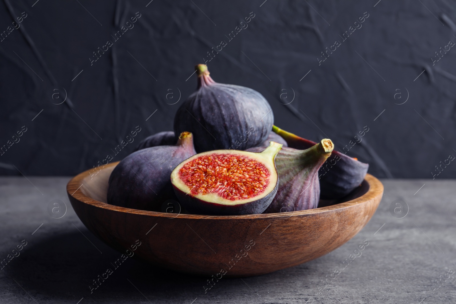 Photo of Bowl with fresh ripe figs on gray table. Tropical fruit