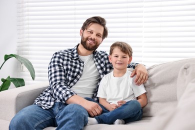 Photo of Family portrait of happy dad and son on sofa at home
