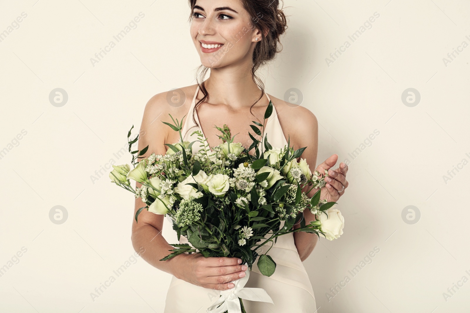 Photo of Young bride wearing wedding dress with beautiful bouquet on light background, closeup