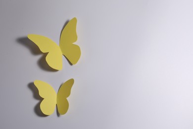 Yellow paper butterflies on light background, top view. Space for text