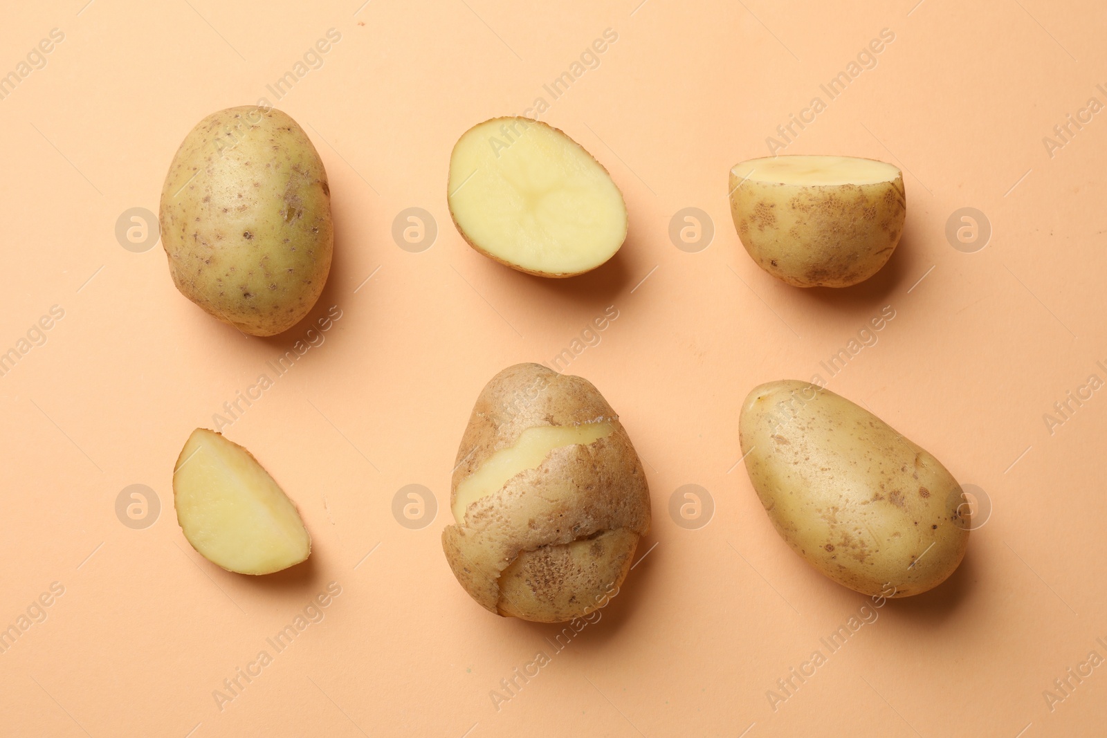 Photo of Fresh raw potatoes on pale orange background, flat lay