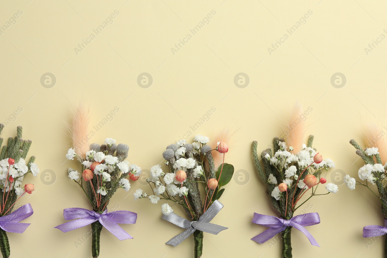 Photo of Many stylish boutonnieres on beige background, flat lay. Space for text