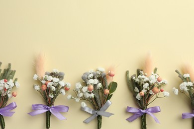 Many stylish boutonnieres on beige background, flat lay. Space for text