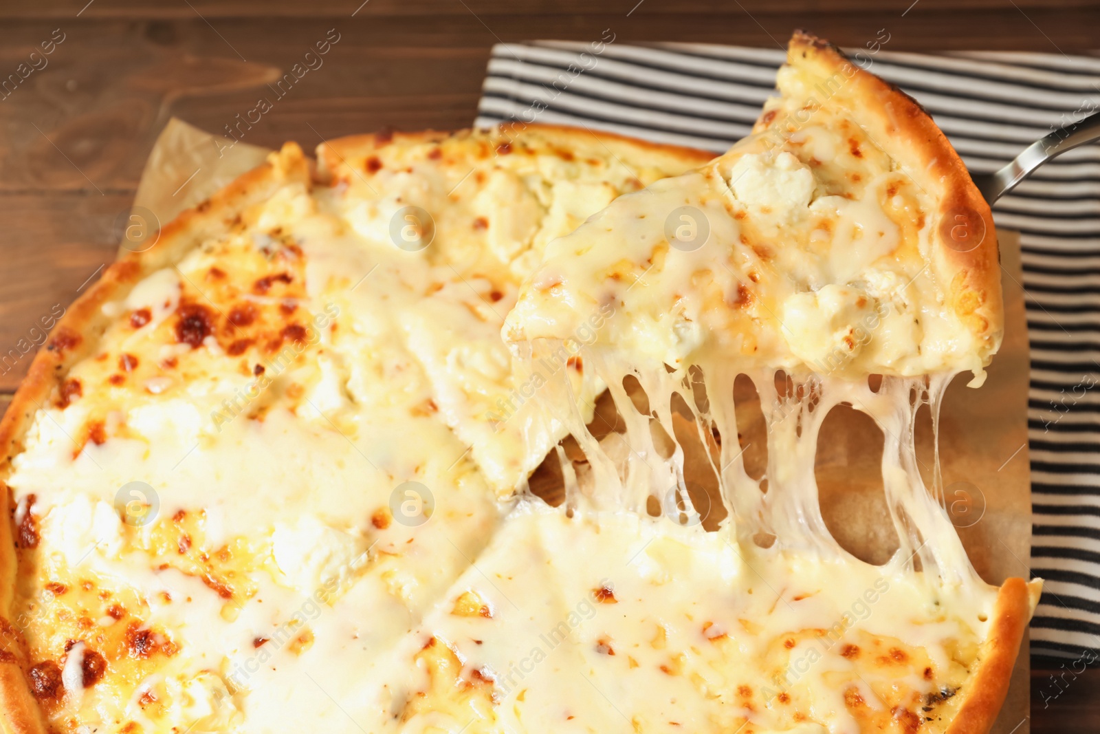 Photo of Shovel with slice of delicious hot pizza over table, closeup