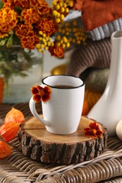 Photo of Cup of drink and autumn flowers on wicker table