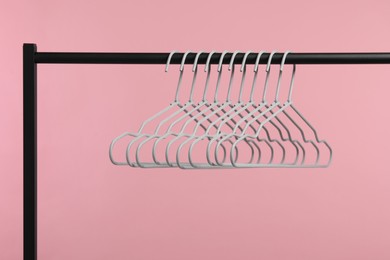 Photo of Empty clothes hangers on rack against pink background