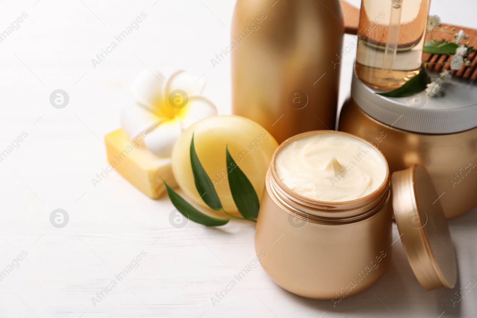 Photo of Set of hair cosmetic products and flowers on white wooden table, closeup. Space for text