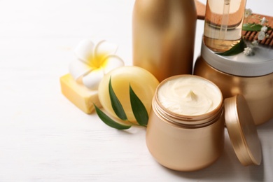 Photo of Set of hair cosmetic products and flowers on white wooden table, closeup. Space for text