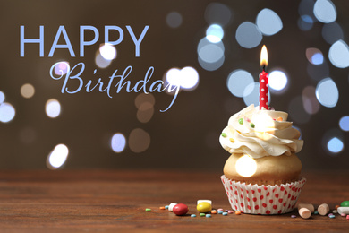 Image of Delicious cupcake with candle on wooden table against blurred lights. Happy Birthday 