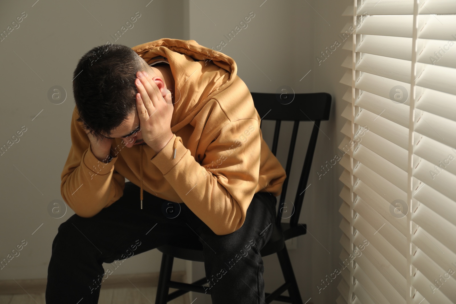 Photo of Sad man sitting on chair near window