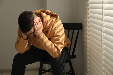 Photo of Sad man sitting on chair near window