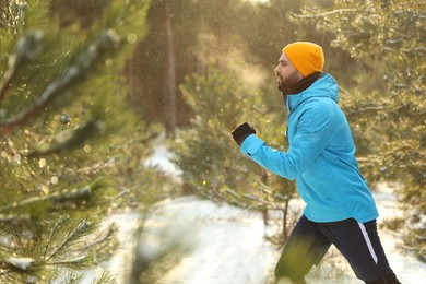 Photo of Young man running in winter forest. Outdoors sports exercises
