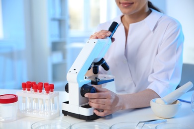 Photo of Female scientist with microscope in chemistry laboratory, closeup