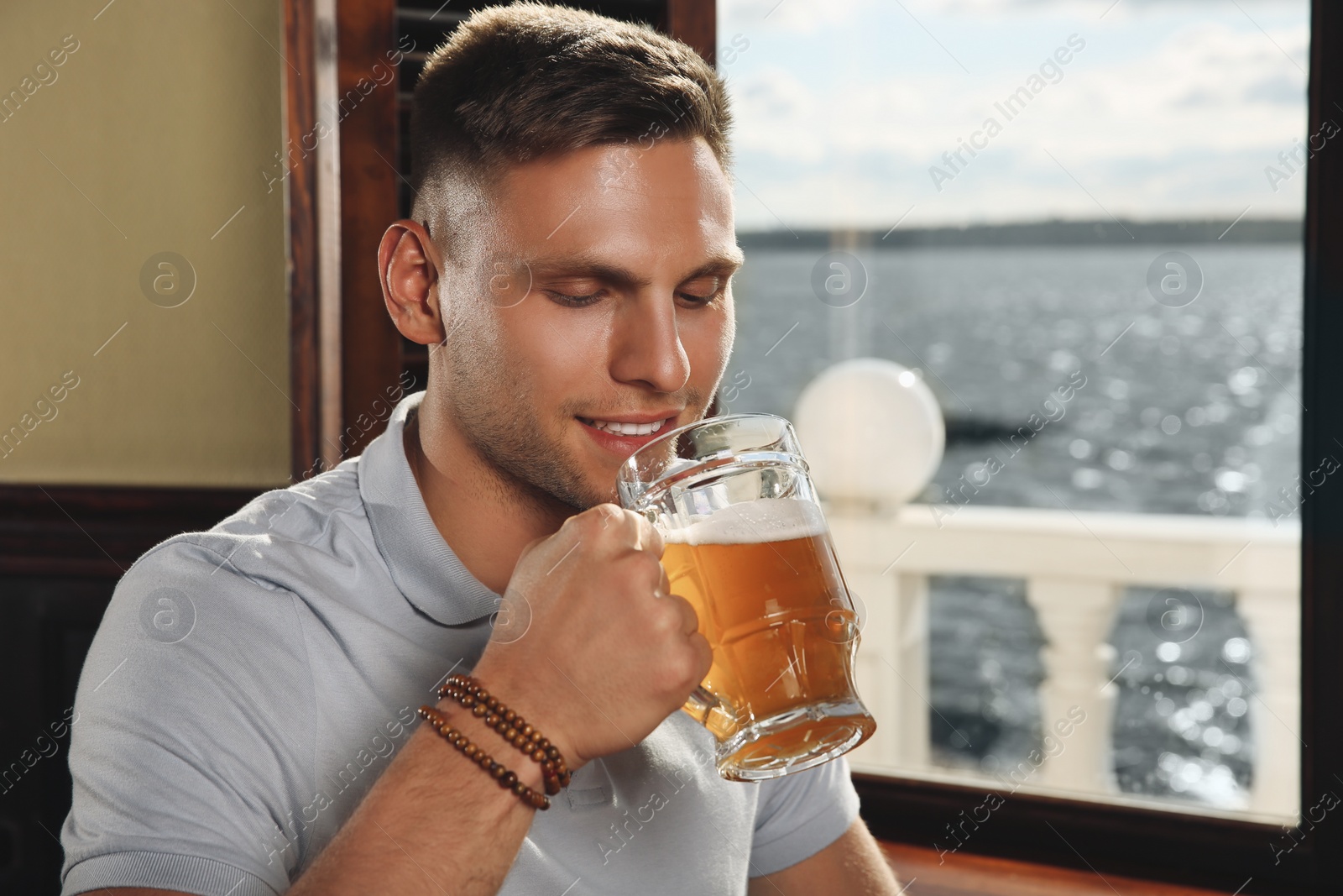 Photo of Young man drinking tasty beer in pub
