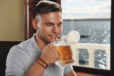 Photo of Young man drinking tasty beer in pub