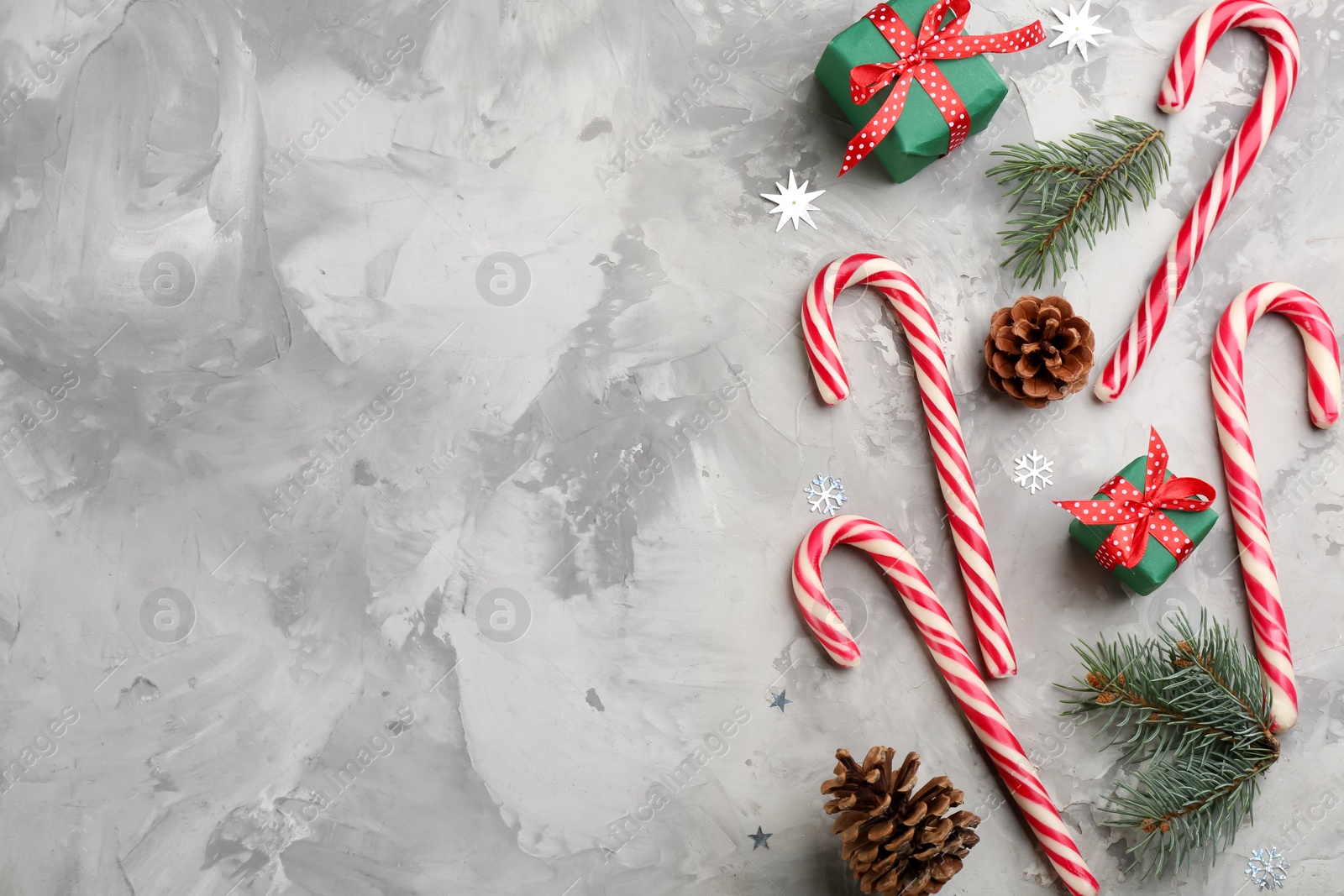 Photo of Flat lay composition with candy canes and Christmas decor on grey table. Space for text