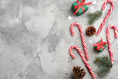 Flat lay composition with candy canes and Christmas decor on grey table. Space for text