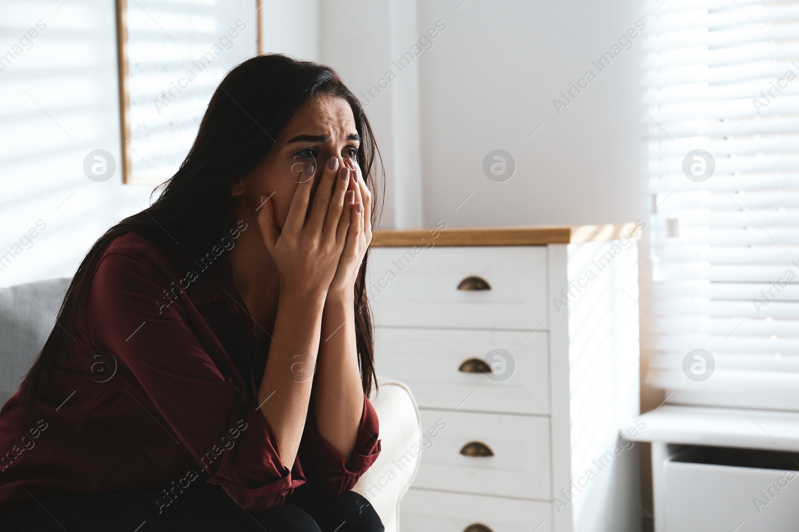 Photo of Abused young woman crying indoors, space for text. Domestic violence concept