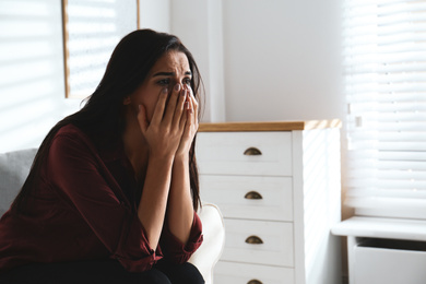 Photo of Abused young woman crying indoors, space for text. Domestic violence concept