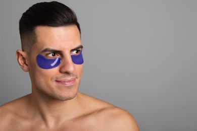 Man with blue under eye patches on grey background. Space for text