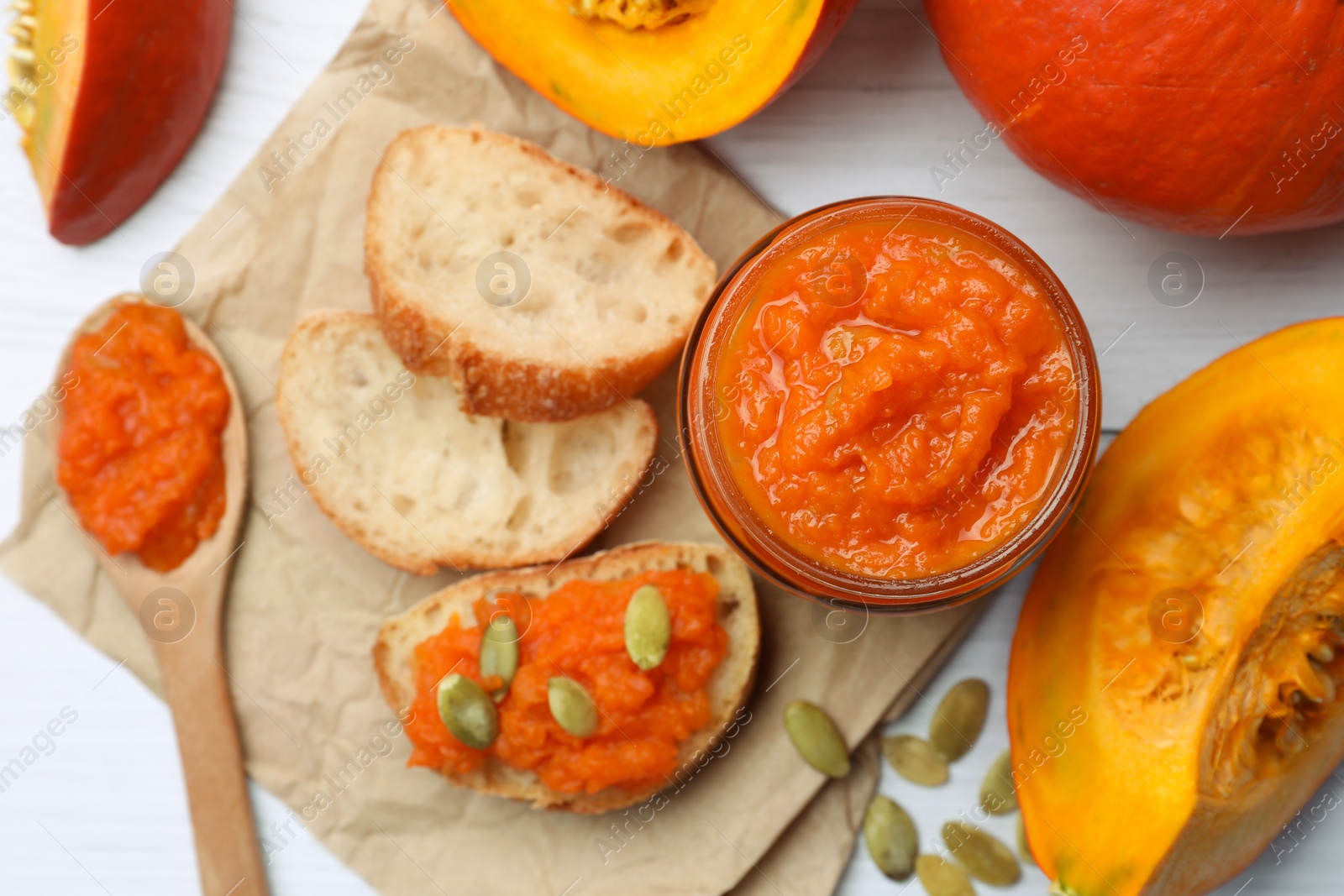 Photo of Delicious pumpkin jam and fresh pumpkin on white wooden table, flat lay