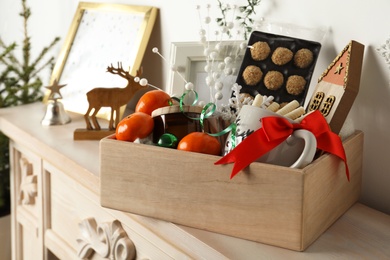 Crate with gift set and Christmas decor on mantelpiece