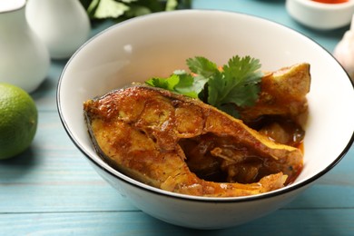 Photo of Tasty fish curry on light blue wooden table, closeup. Indian cuisine