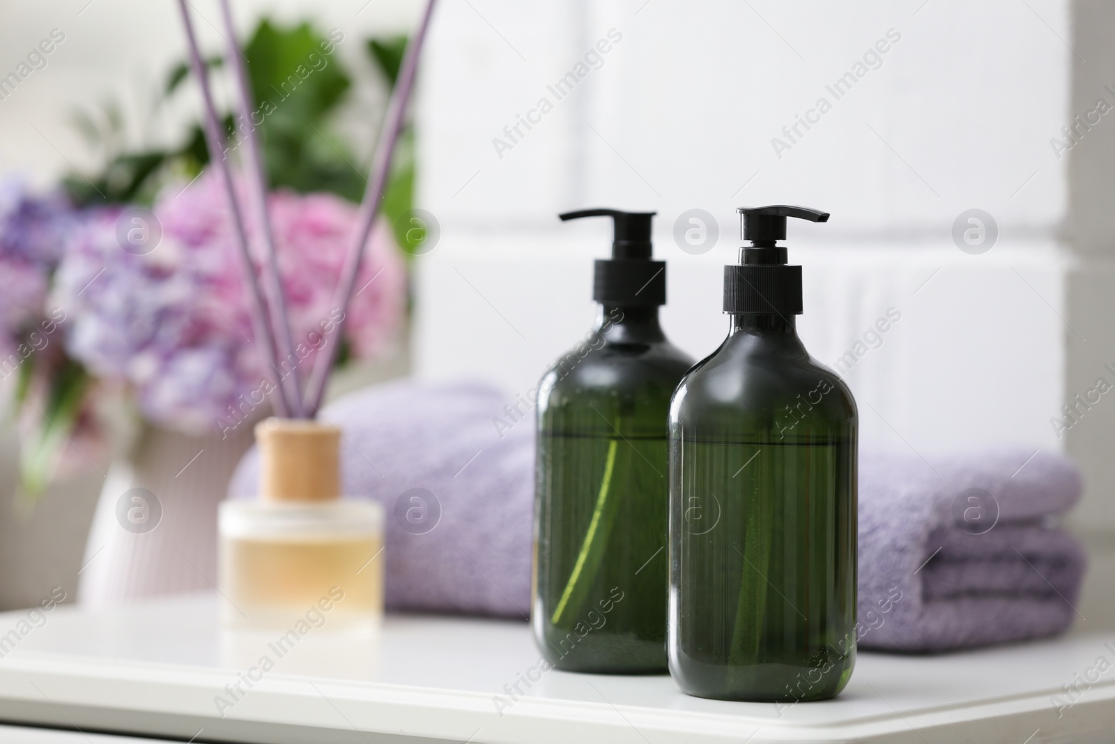 Photo of Soap dispensers and clean towel on white table. Space for text