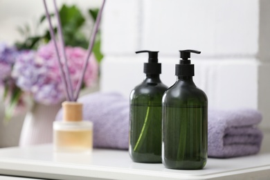 Soap dispensers and clean towel on white table. Space for text