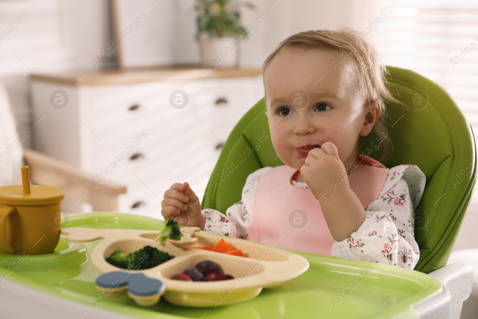 Photo of Cute little baby wearing bib while eating at home