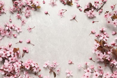Photo of Frame of beautiful spring tree blossoms on light stone table, flat lay. Space for text