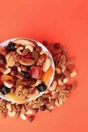Photo of Bowl with mixed dried fruits and nuts on orange background, flat lay