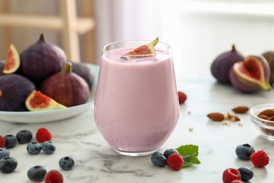 Delicious fig smoothie in glass on white marble table