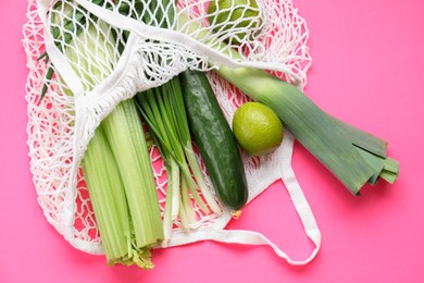 String bag with different vegetables on bright pink background, top view