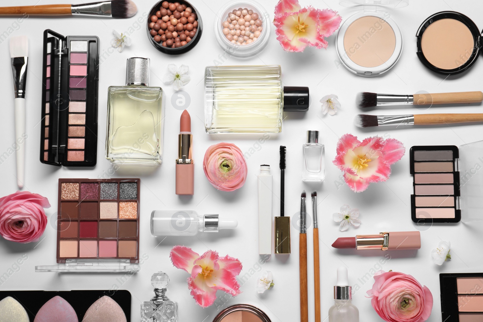 Photo of Flat lay composition with different makeup products and beautiful spring flowers on white background