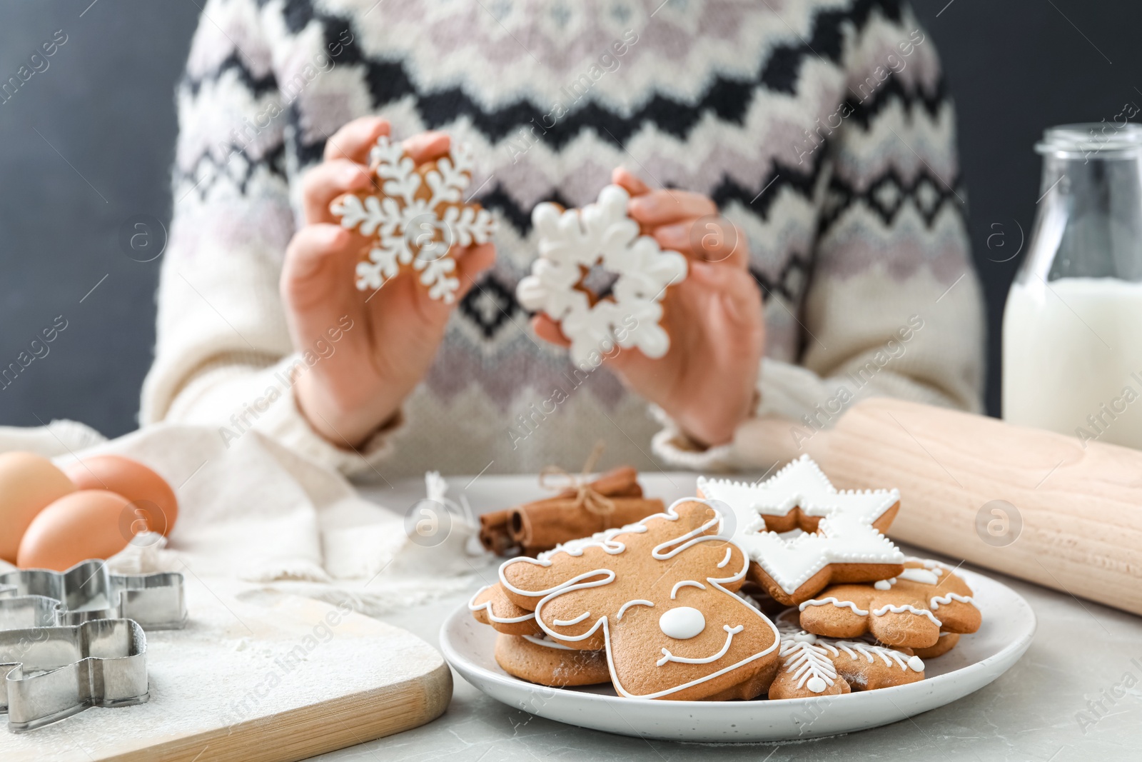 Photo of Woman holding delicious homemade Christmas cookies at grey marble table, focus on plate