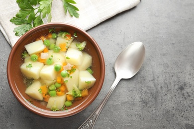 Photo of Bowl of fresh homemade vegetable soup served on grey table, flat lay. Space for text