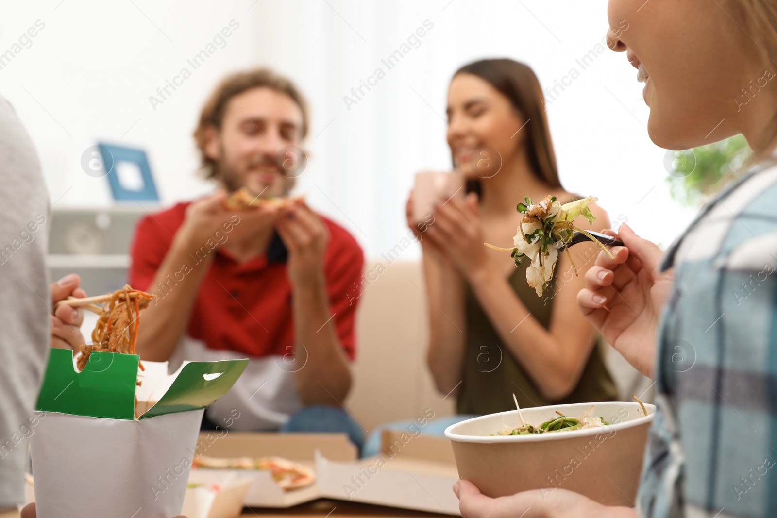 Photo of Young people having lunch together at home. Food delivery