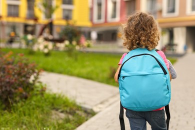Photo of Little girl walking to kindergarten outdoors, back view. Space for text
