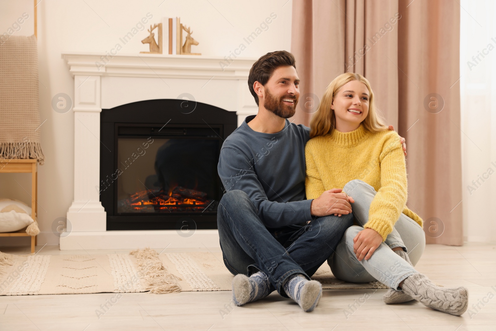 Photo of Lovely couple spending time together near fireplace indoors