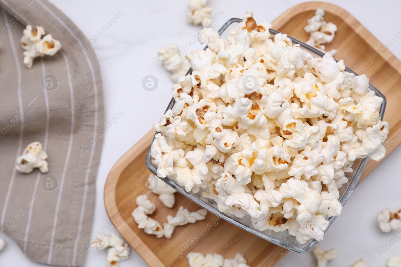 Photo of Bowl of tasty popcorn on white table, flat lay. Space for text