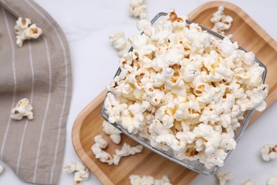 Photo of Bowl of tasty popcorn on white table, flat lay. Space for text