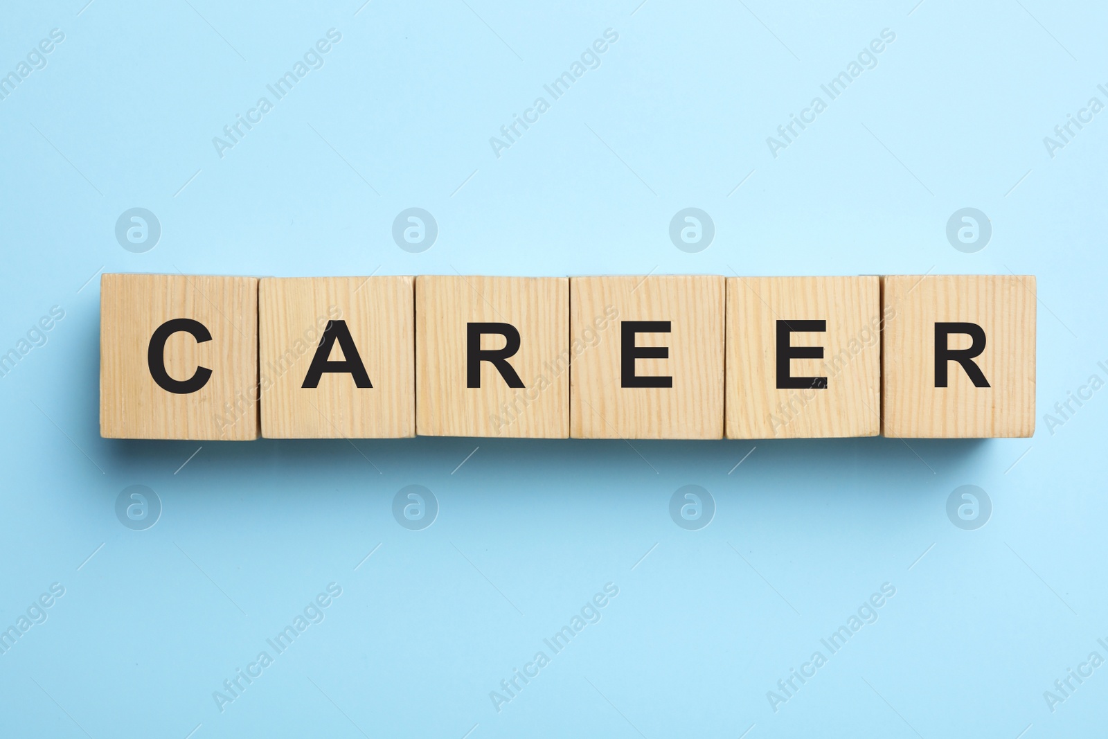 Photo of Wooden cubes with word CAREER on light blue background, flat lay