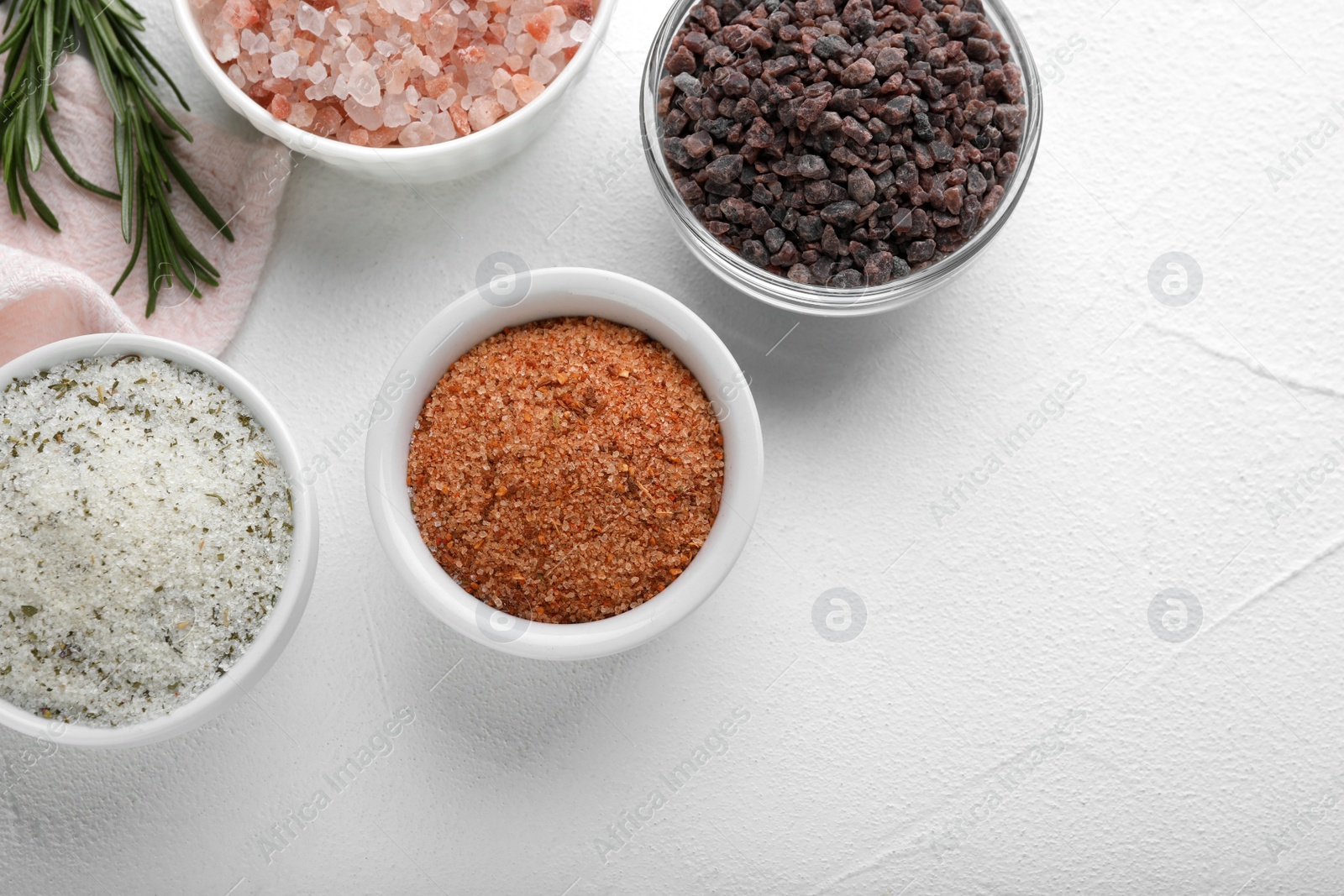 Photo of Different kinds of salt on white table, flat lay. Space for text