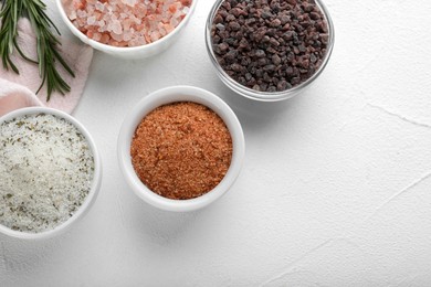 Different kinds of salt on white table, flat lay. Space for text