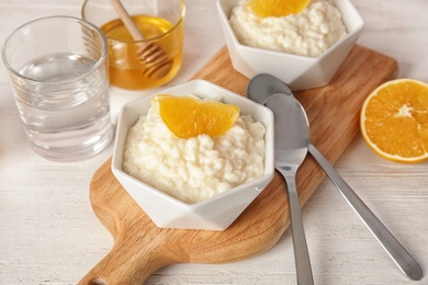 Photo of Creamy rice pudding with orange slices in bowls served on wooden table