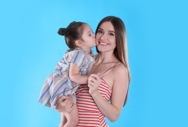 Young mother and little daughter on blue background