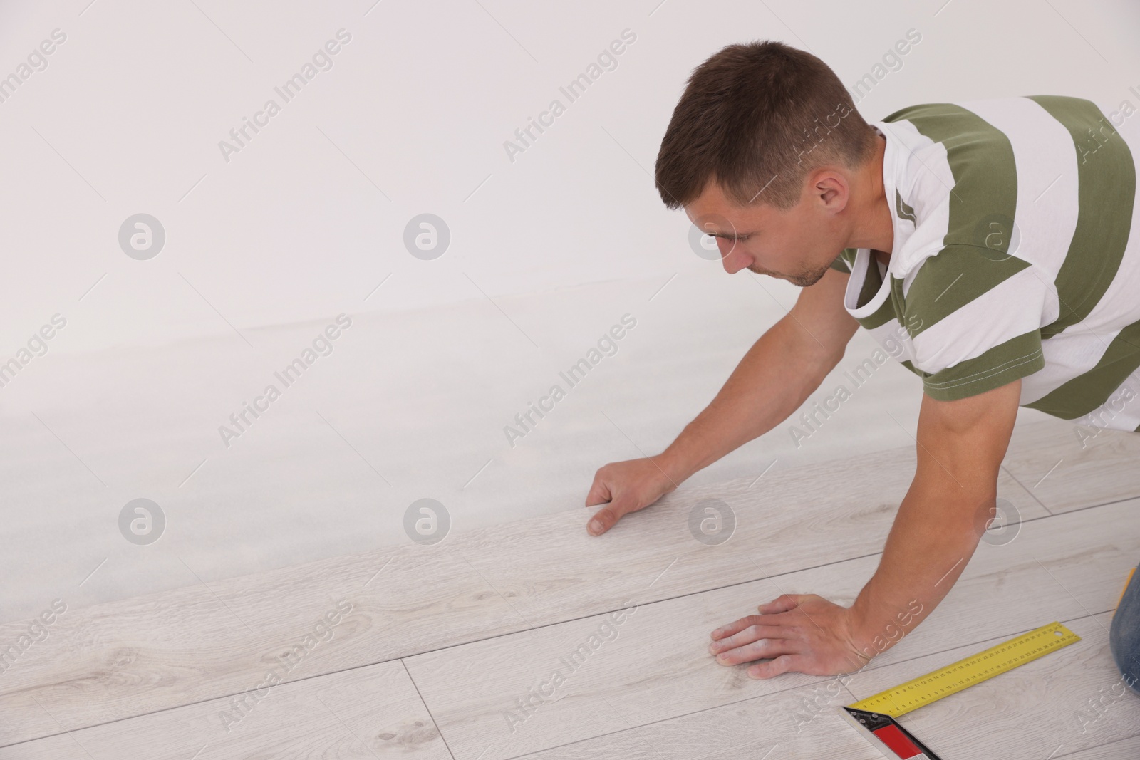 Photo of Professional worker installing new laminate flooring indoors